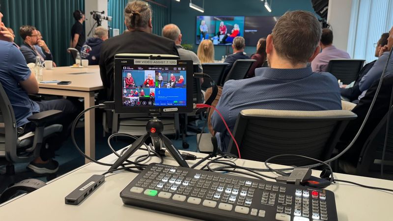 Livestream-Setup im Besprechungsraum mit Bildmischer und Kontrollmonitor vor Publikum