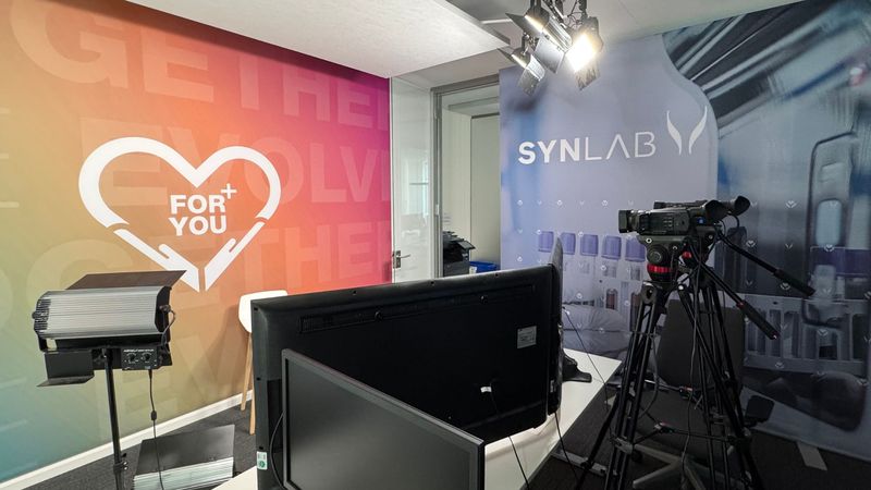 Inhouse-Studio-Set mit Kamera auf Stativ, Dauerlicht und Monitor vor farbiger Wand